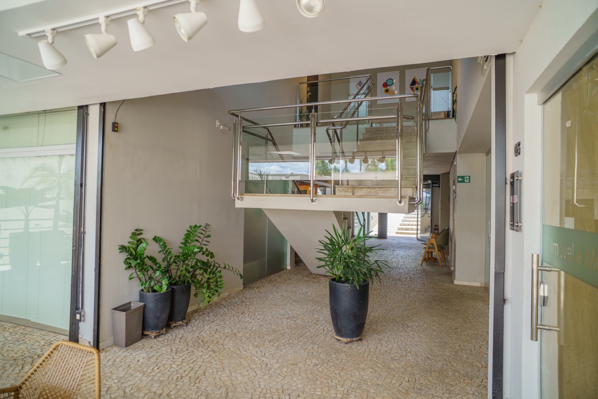 Hall interno da Via Sul Empresarial com escadaria, plantas e iluminação moderna