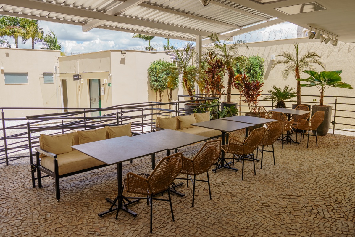 Área lounge da Via Sul Empresarial com mesas, sofás e jardim tropical